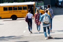 teens walking towards a parked school bus