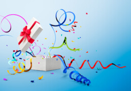 Ribbon and confetti popping out from gift box over blue background